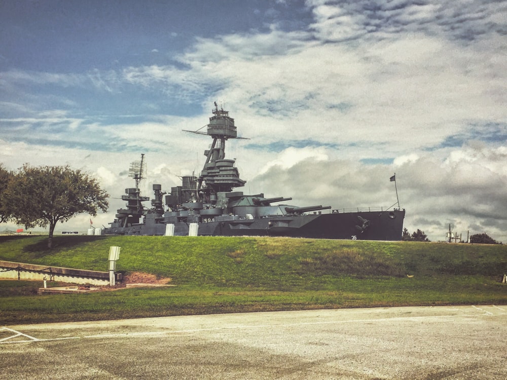 a large battleship sitting on top of a lush green field
