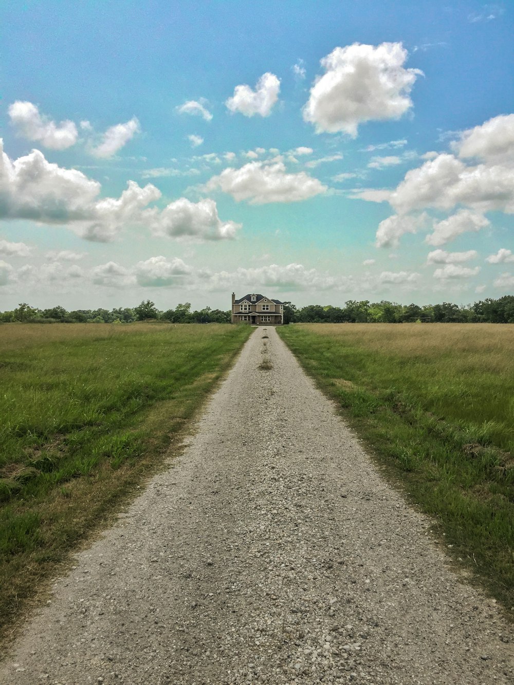 a dirt road with a house in the distance