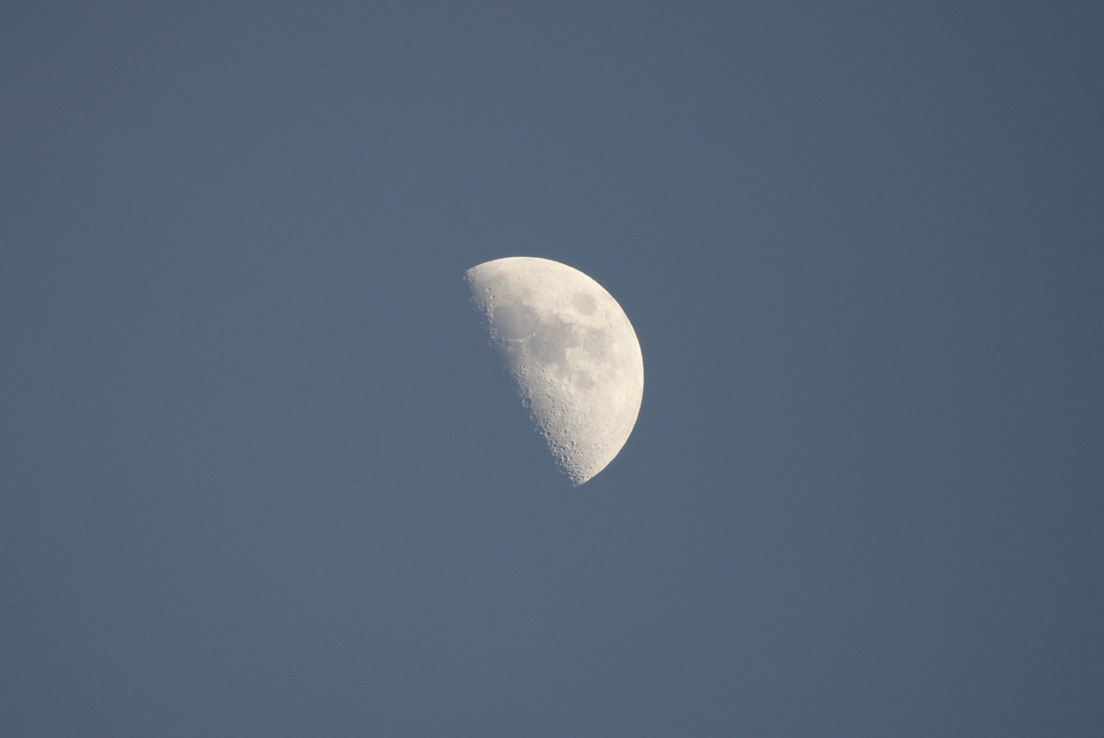 a half moon in a clear blue sky