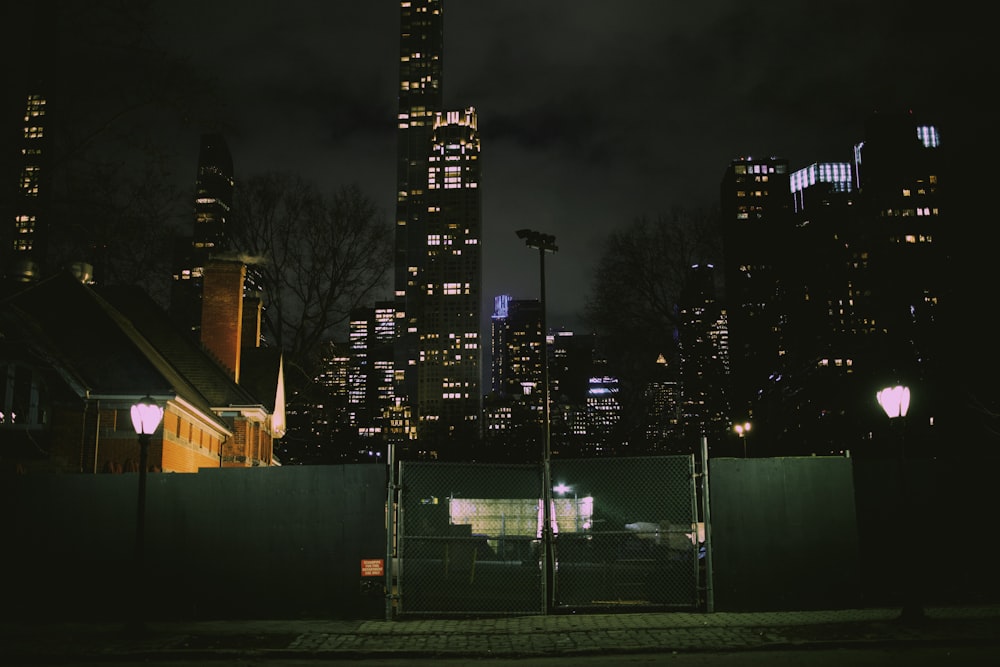 a night view of a city with a fence in the foreground