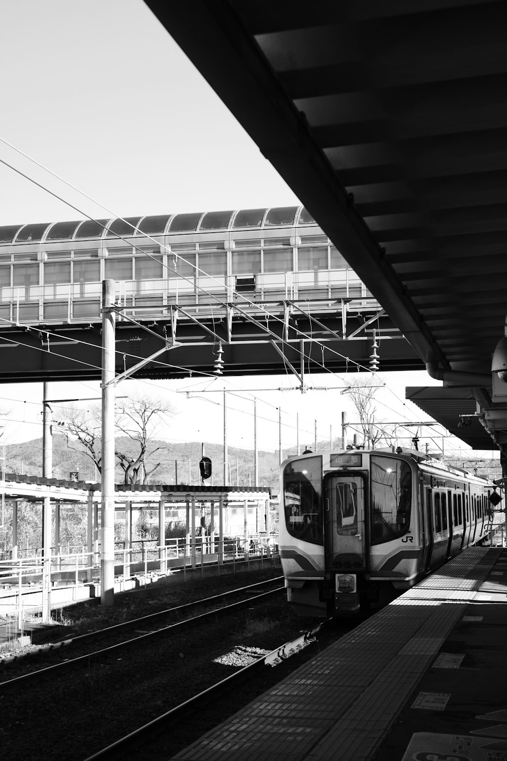 Una foto in bianco e nero di un treno in una stazione ferroviaria