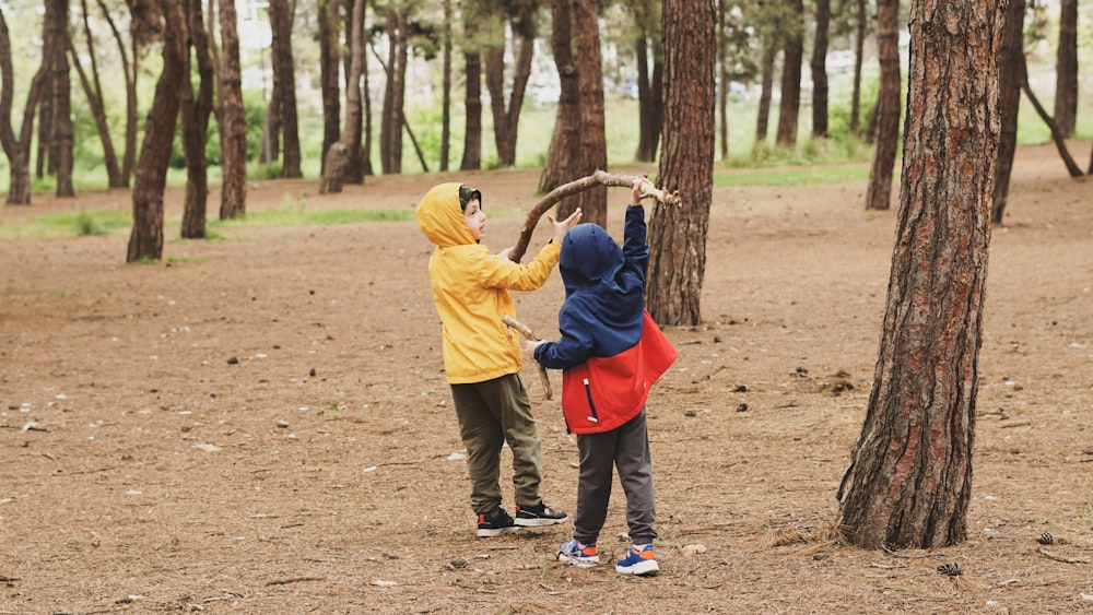 a couple of kids standing next to each other in a forest