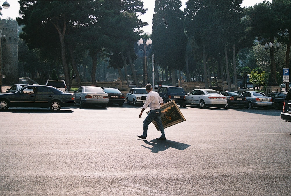 a man walking across a parking lot holding a suitcase