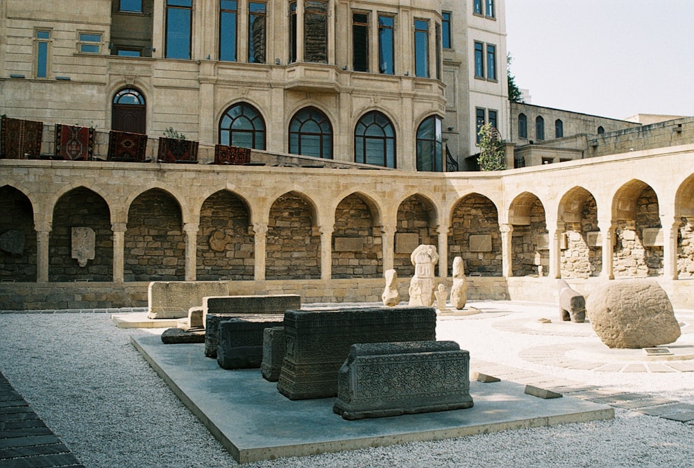 a courtyard with stone sculptures and a building in the background