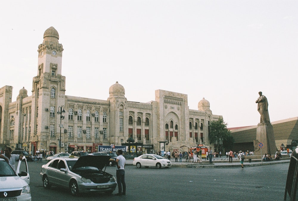 a city street with cars and a statue in front of a building