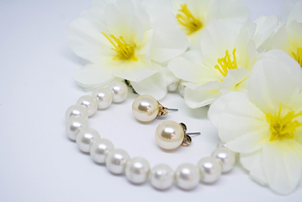 a pair of pearls and a flower on a white surface
