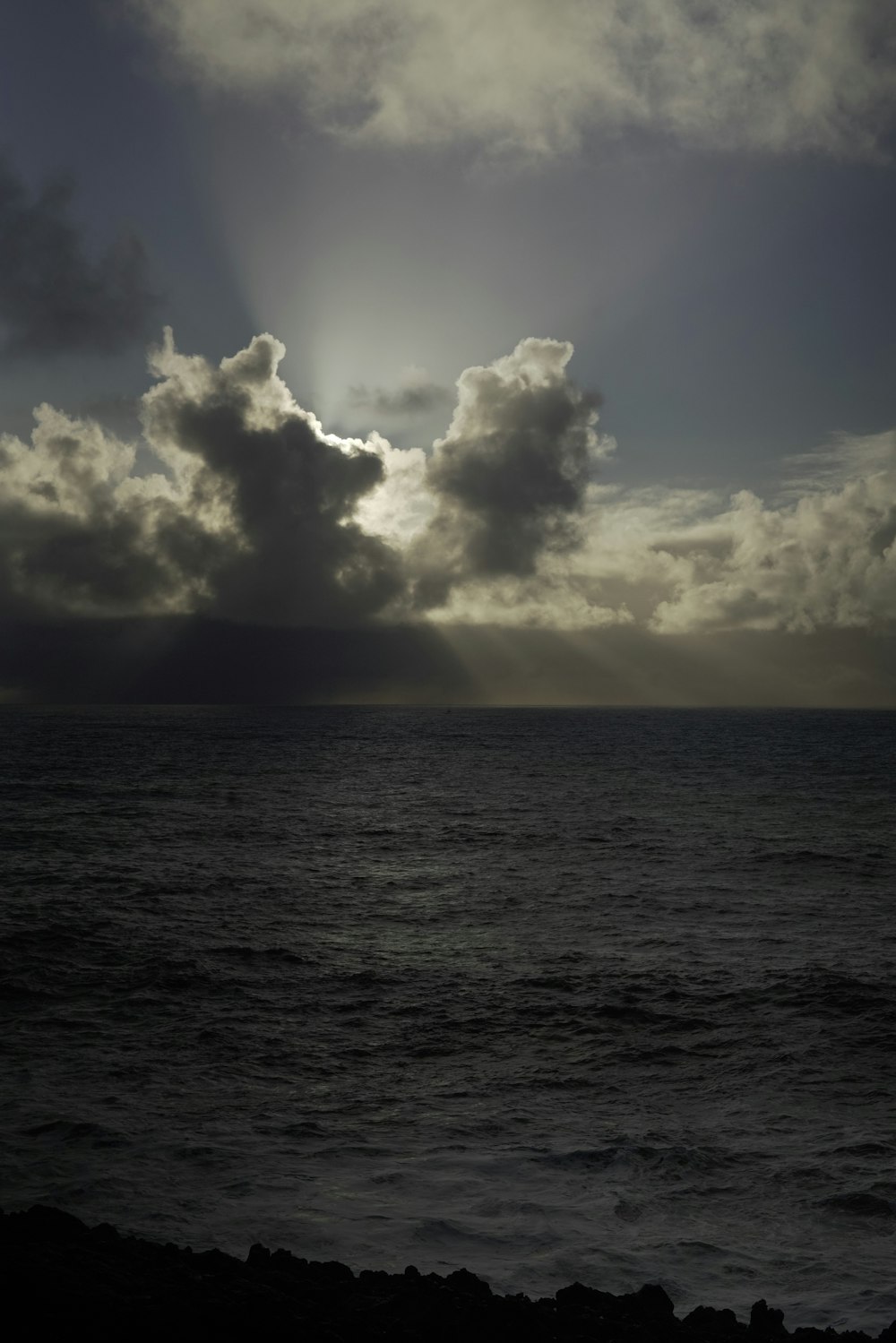 the sun shining through the clouds over the ocean