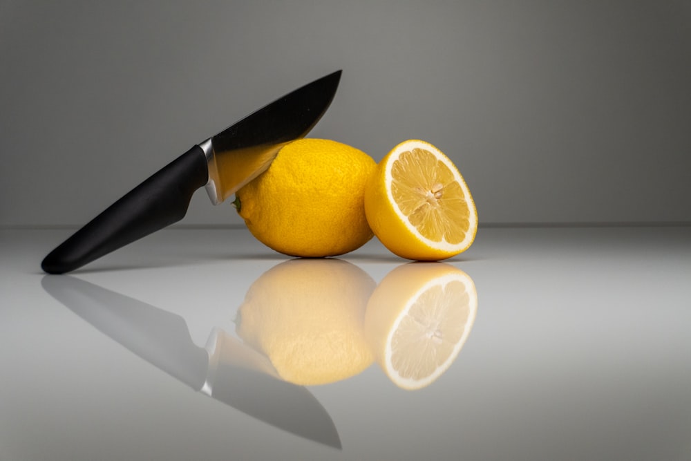 a knife and two lemons on a reflective surface