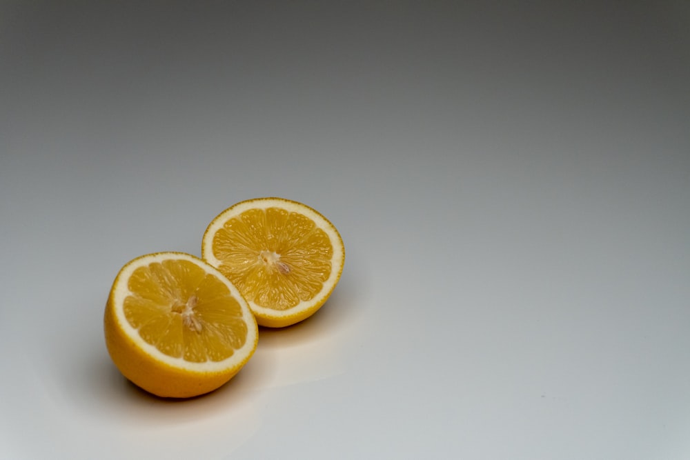 two halves of a lemon on a white surface