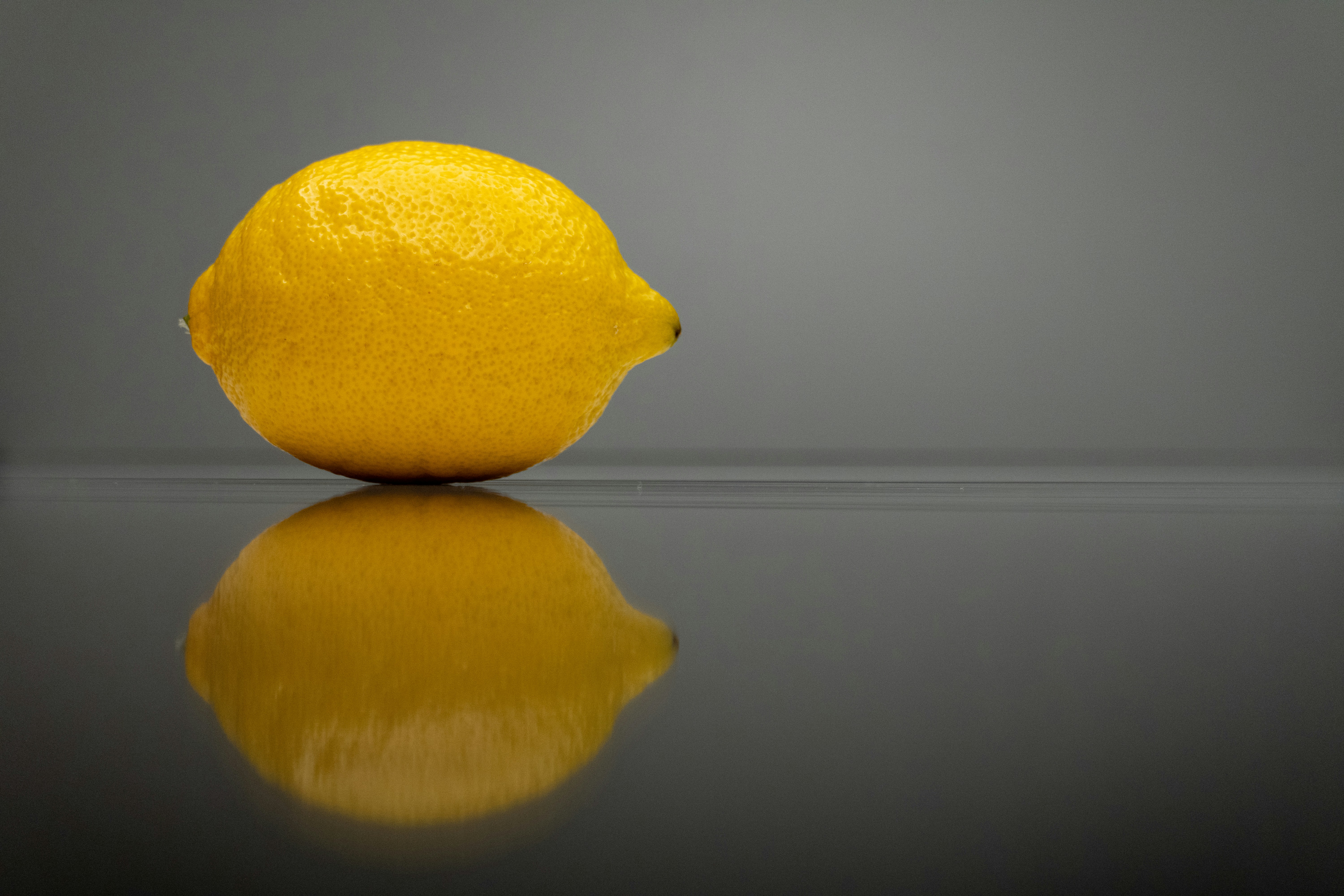 a yellow lemon sitting on top of a reflective surface