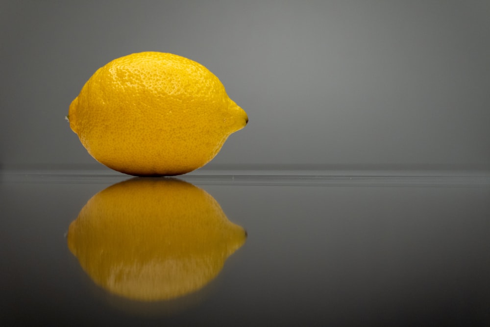 a yellow lemon sitting on top of a reflective surface