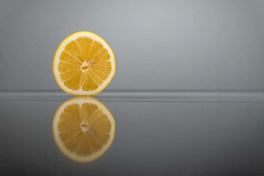 a slice of orange sitting on top of a reflective surface