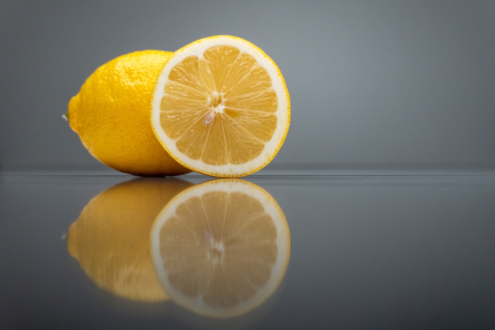 two lemons sitting side by side on a reflective surface