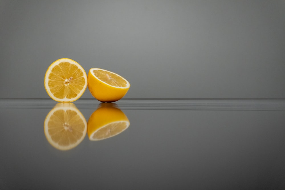 a couple of oranges sitting on top of a reflective surface