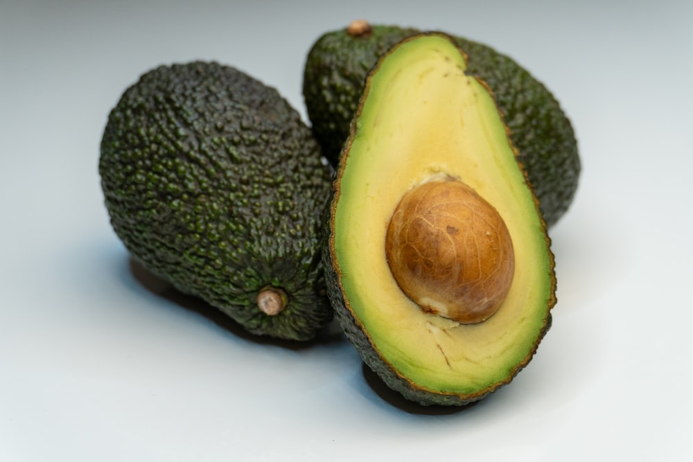 an avocado cut in half on a white surface