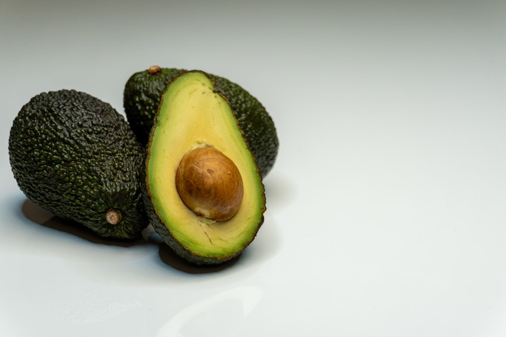 an avocado cut in half on a white surface