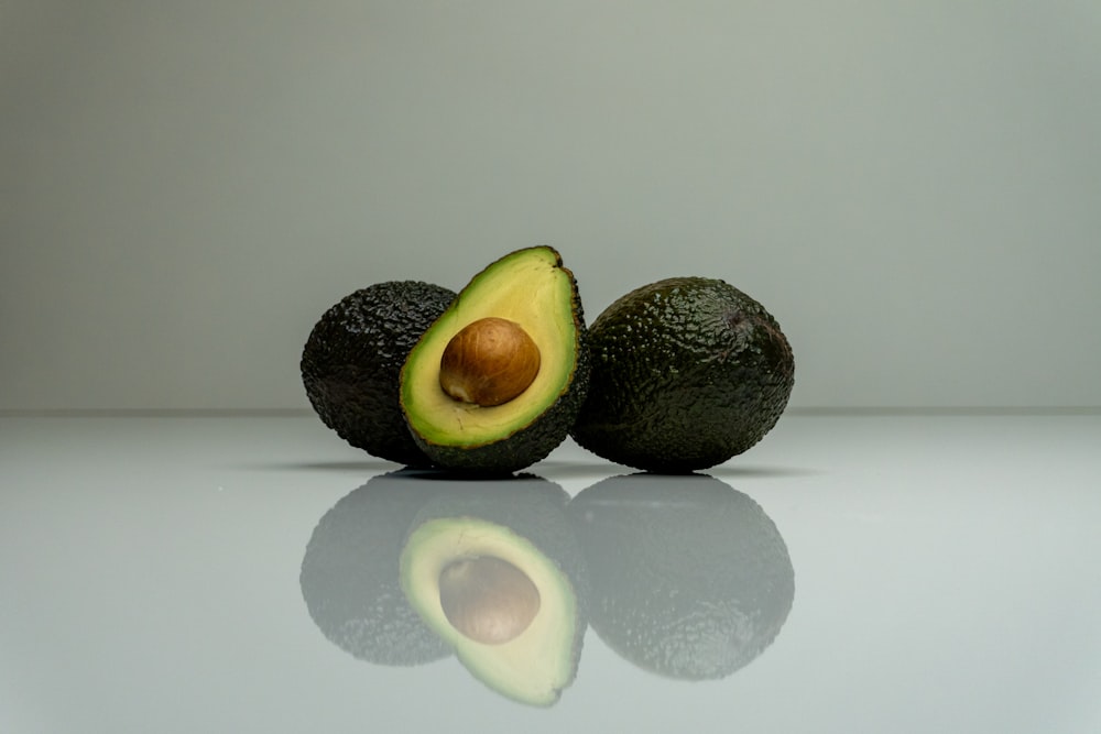 an avocado cut in half on a reflective surface