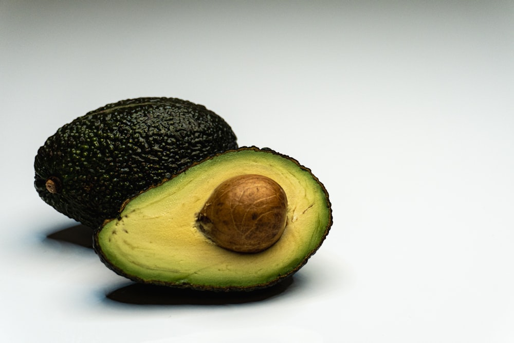 an avocado cut in half on a white surface