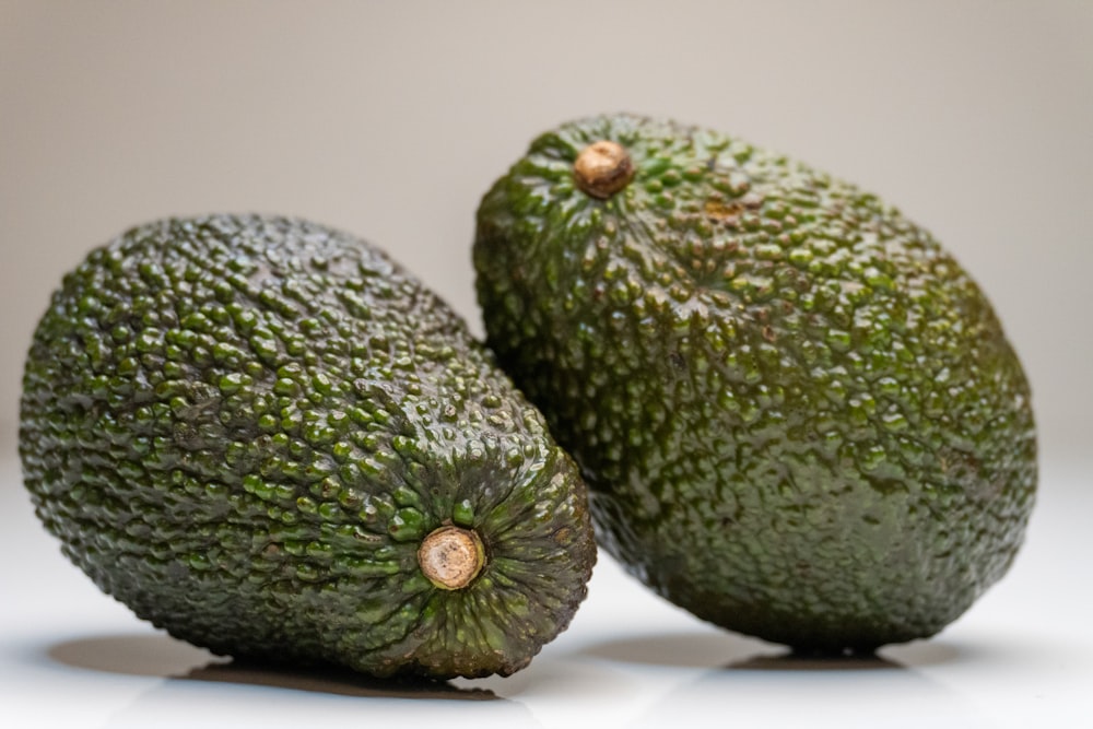 two avocados sitting next to each other on a table