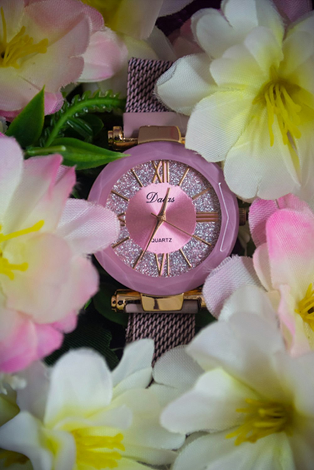 a pink watch surrounded by pink and white flowers