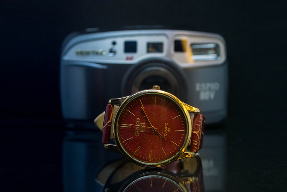 a watch sitting on top of a table next to a camera