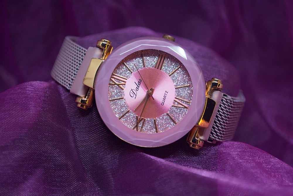 a close up of a watch on a purple cloth