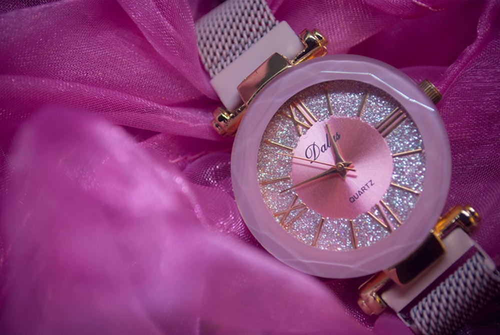 a close up of a watch on a pink cloth