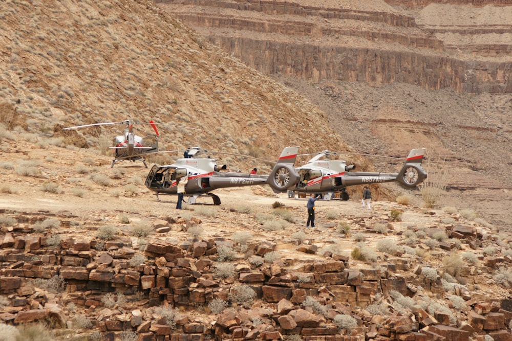 a couple of small airplanes parked on top of a dirt field