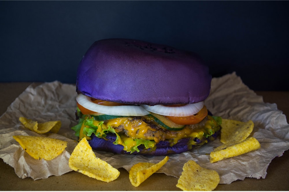 a hamburger with a purple bun and lettuce and cheese