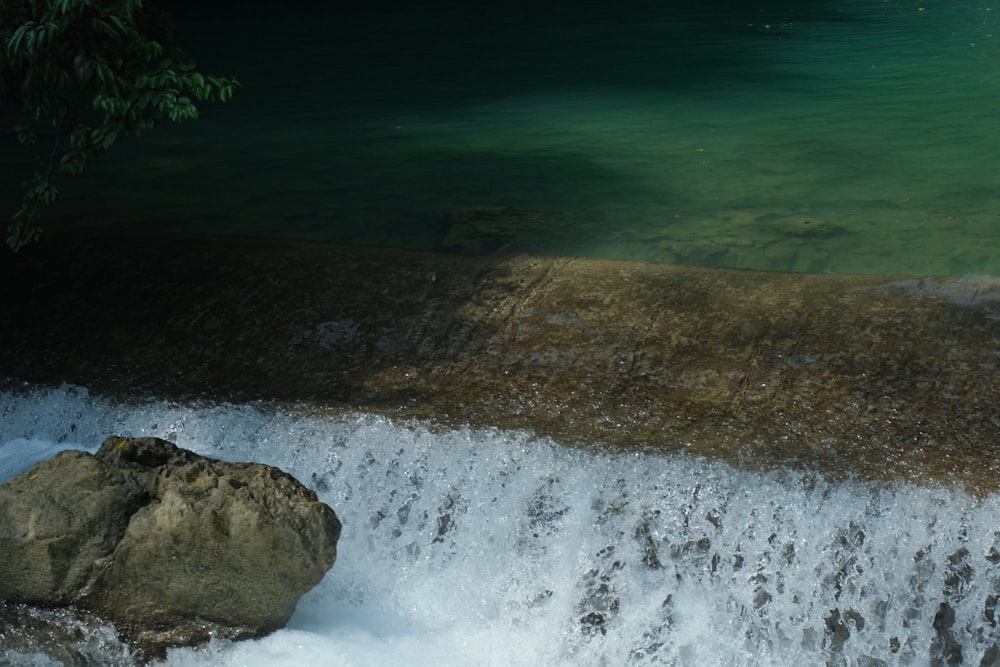 a large rock sitting next to a waterfall