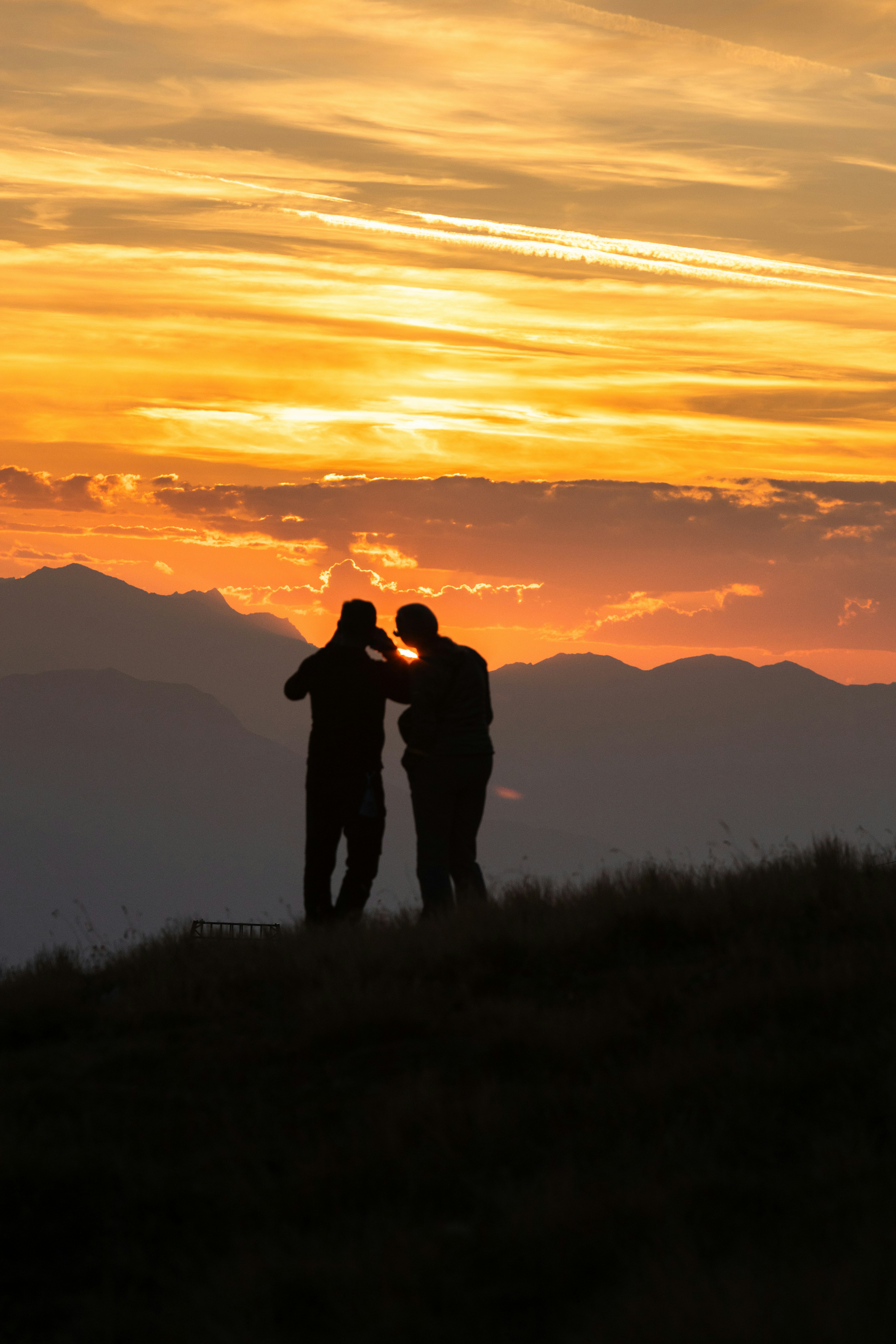 a couple of people standing on top of a grass covered hill
