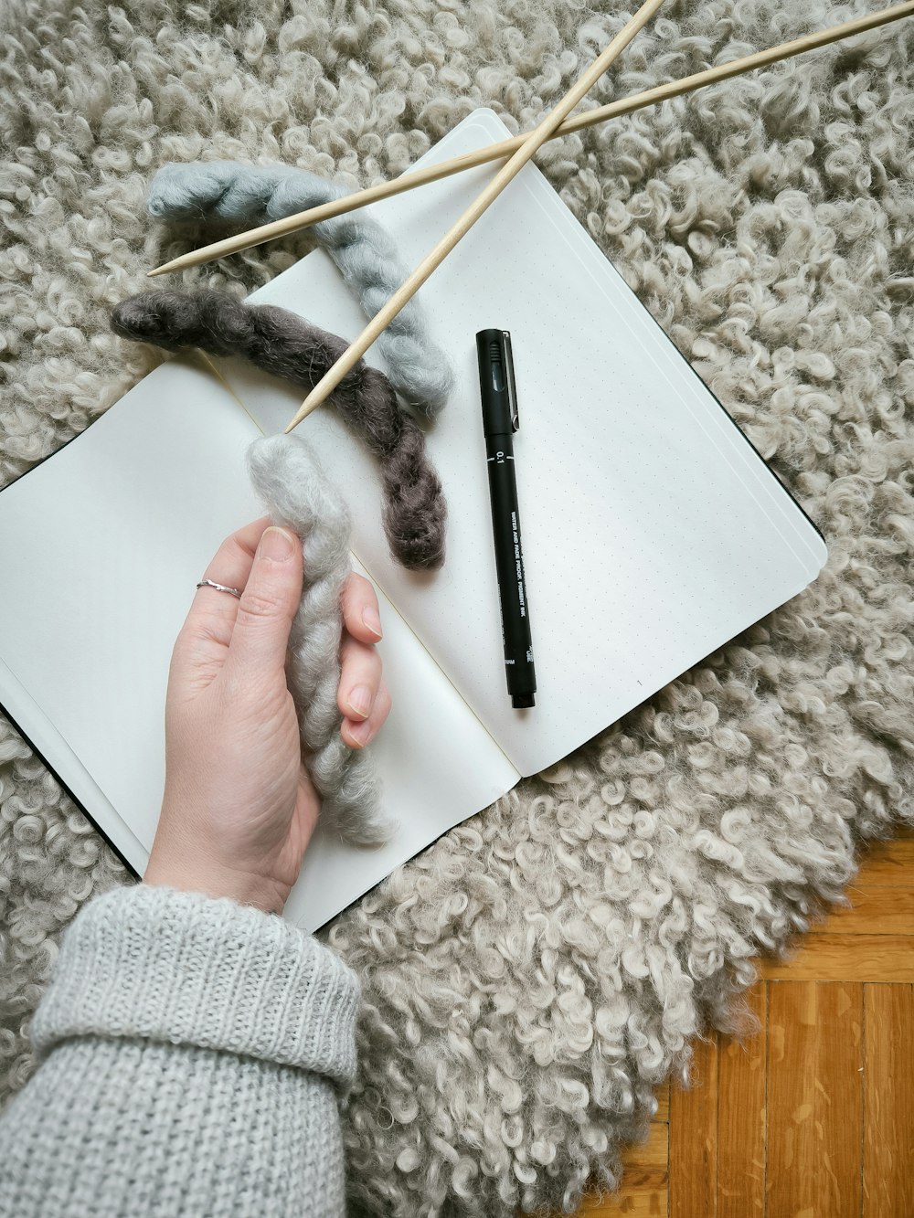 a person is knitting on a piece of paper