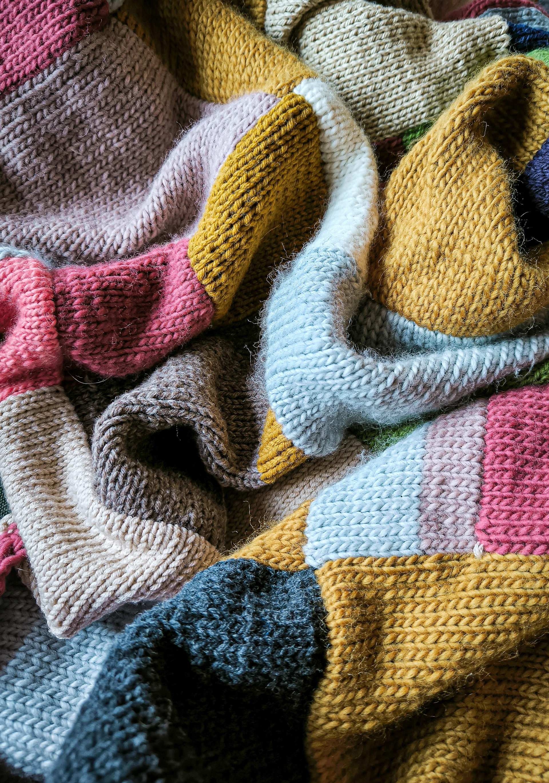 a knitted teddy bear laying on top of a blanket