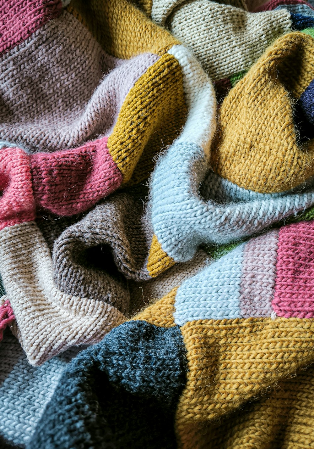 a knitted teddy bear laying on top of a blanket