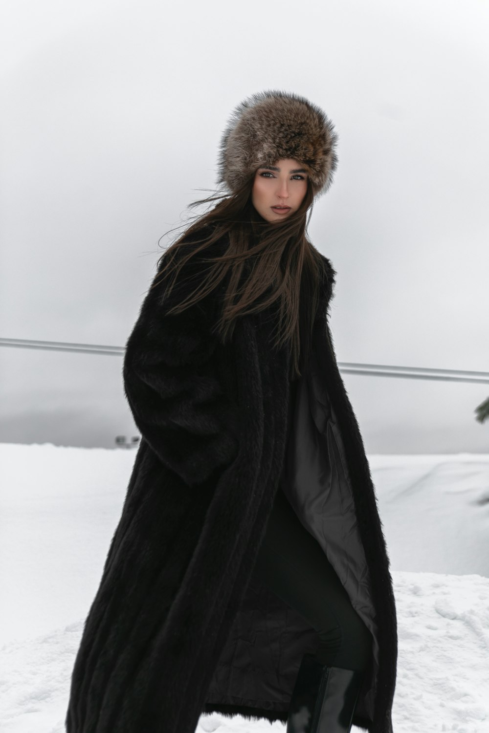 a woman standing in the snow wearing a fur hat