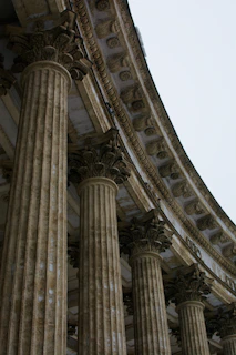 a building with many pillars and a clock on the side of it