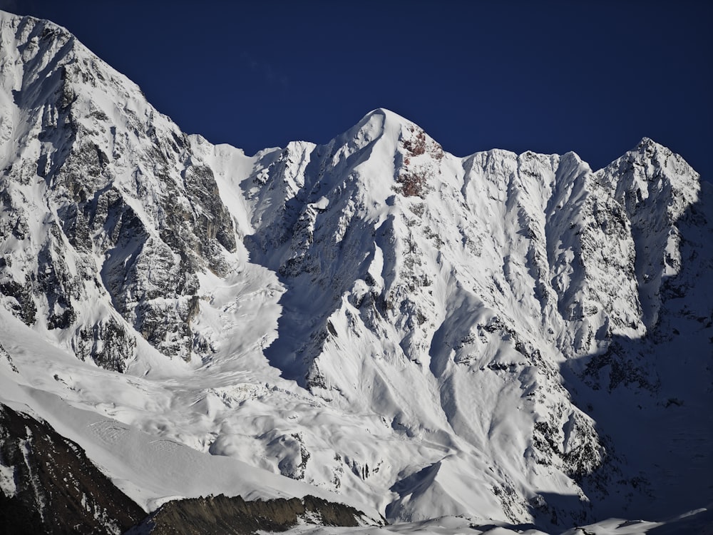 a large mountain covered in snow under a blue sky