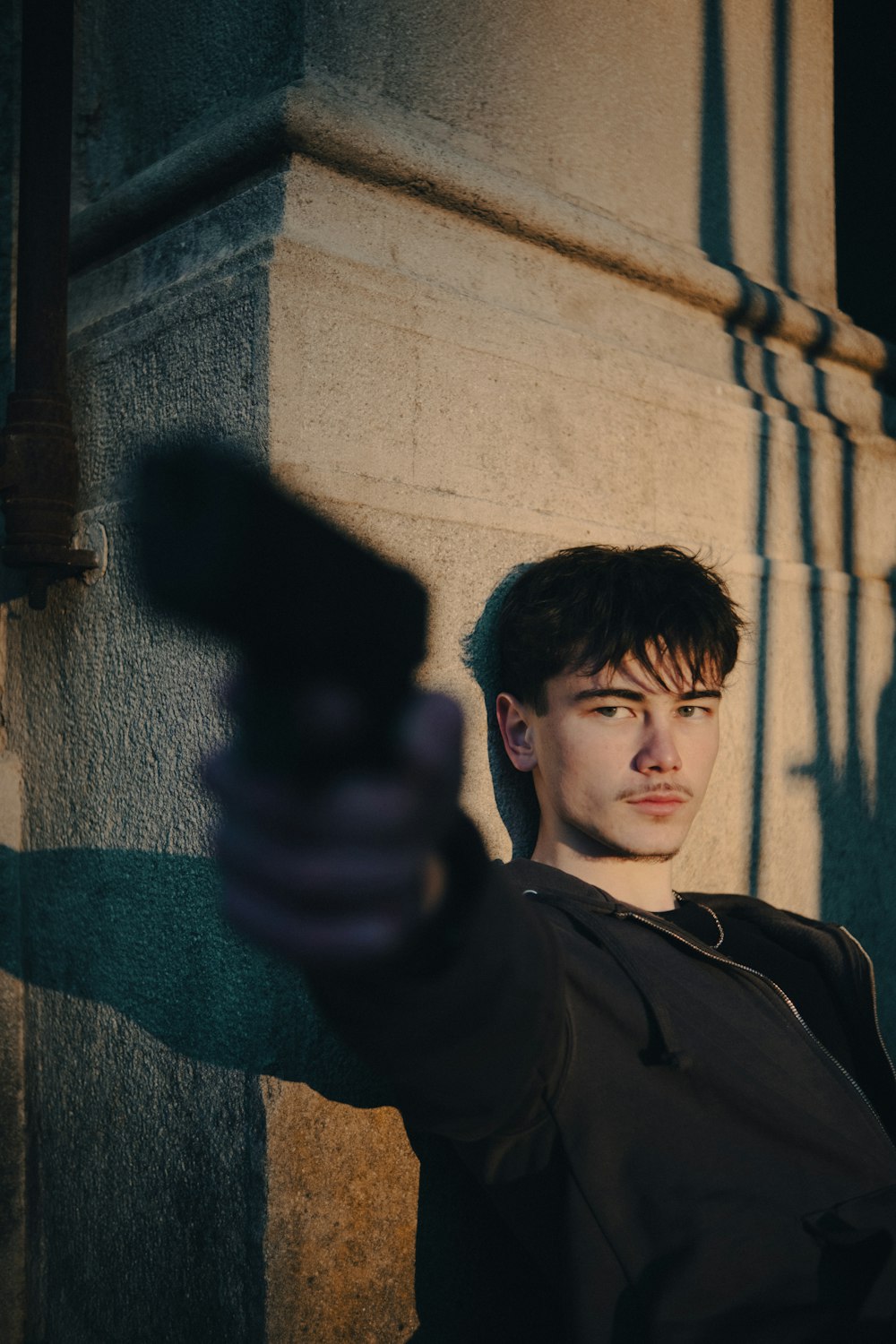 Un hombre apuntando con una pistola a la cámara