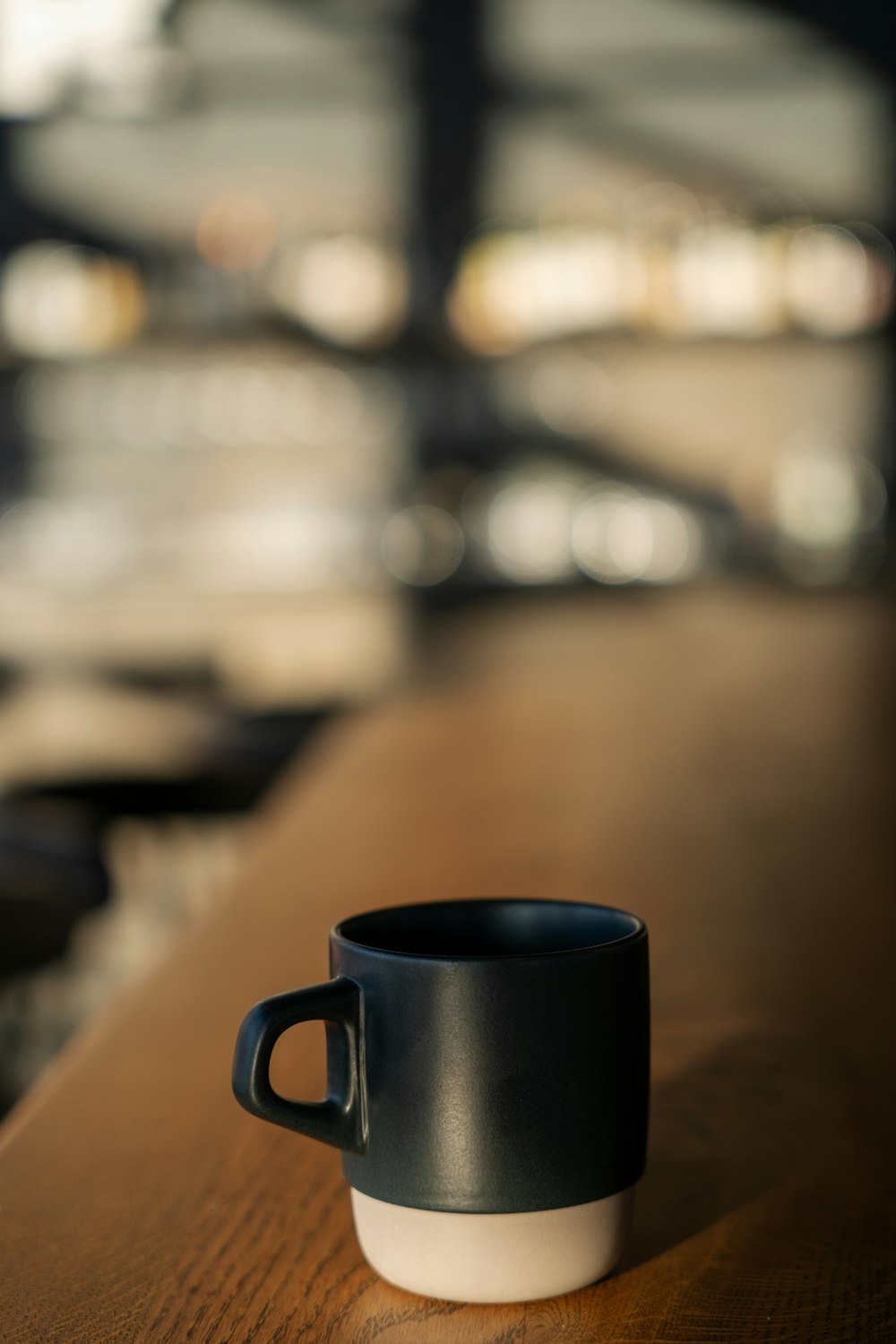a black and white cup sitting on top of a wooden table