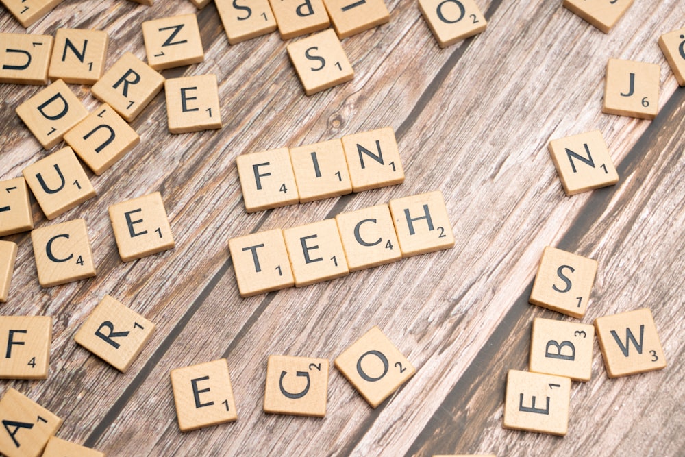 scrabble tiles spelling the word fin tech on a wooden surface