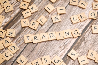 scrabble tiles spelling the word trading on a wooden surface