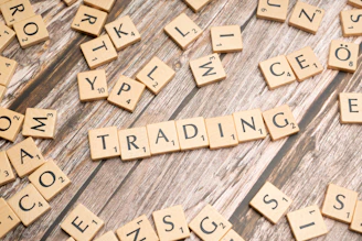 scrabble tiles spelling the word trading on a wooden surface