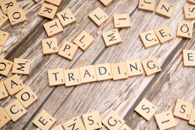 scrabble tiles spelling the word trading on a wooden surface