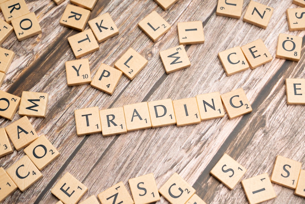 scrabble tiles spelling the word trading on a wooden surface