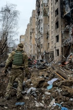 a man in camouflage walking through a destroyed building