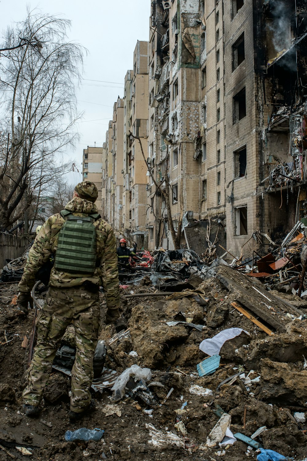 a man in camouflage walking through a destroyed building