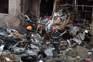 a couple of firemen standing next to a pile of rubble