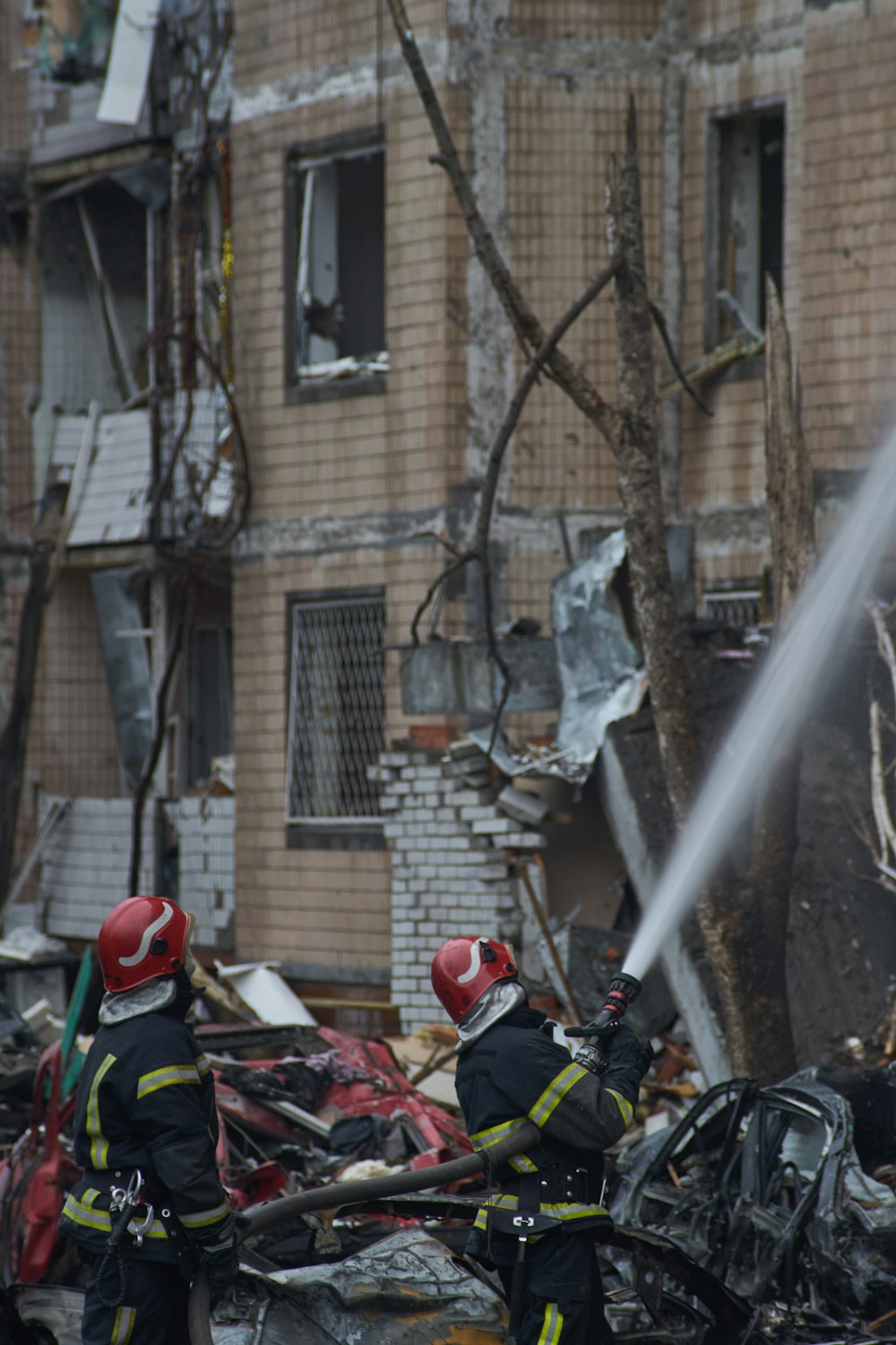 two firemen are spraying water on a building