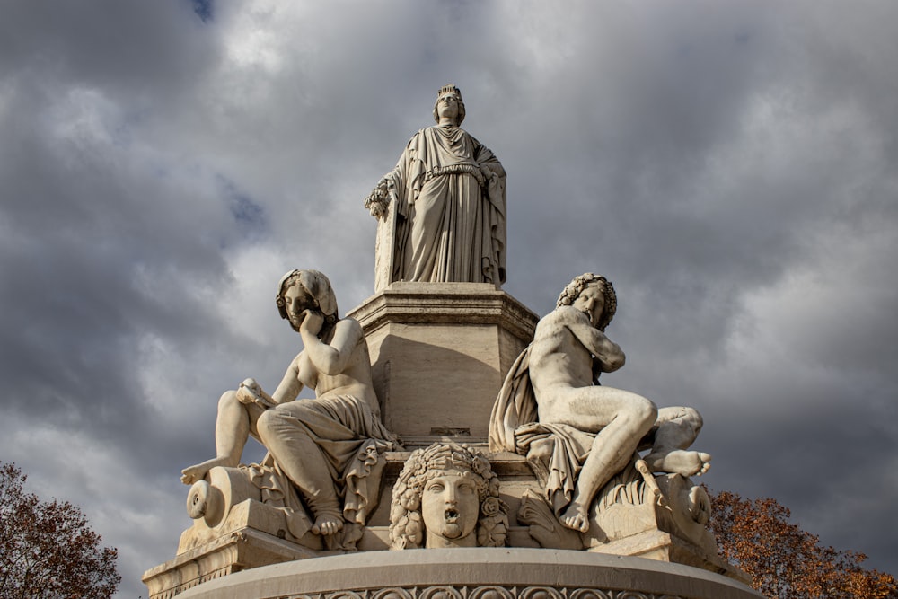 a statue on top of a fountain with statues around it