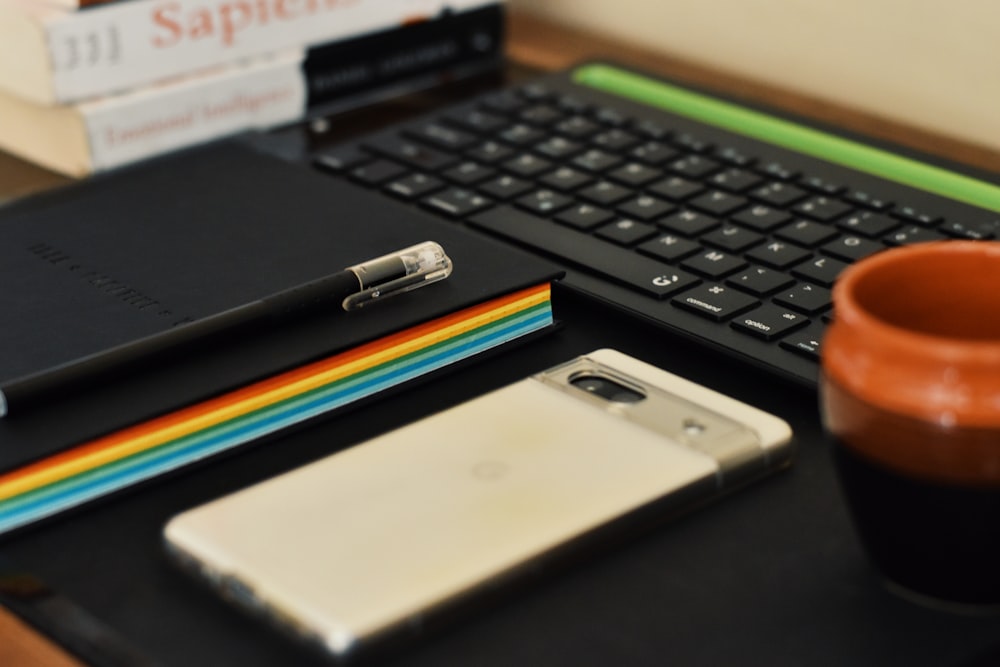 a desk with a laptop, notebook, pen and a cup of coffee